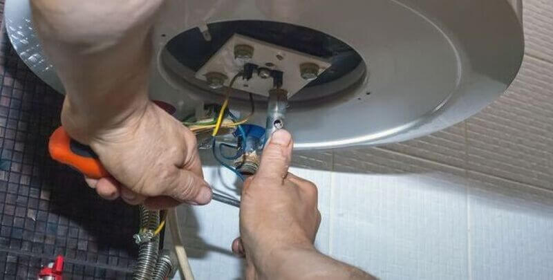 A plumber works on a hot water system
