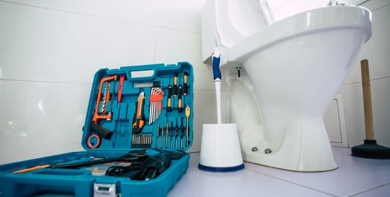 close up photo of ceramic bowl toilet in domestic bathroom with a box of tools